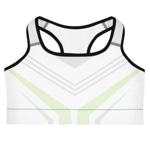 May include: A white sports bra featuring a racerback design with black trim along the neckline and armholes. The front displays a geometric pattern of light gray and pale lime green diagonal lines that converge toward the center hem.