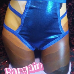 Puede incluir: Ropa interior azul metálico con ribetes azules y detalles recortados. Se muestra en un maniquí con tonos de piel pintados. El texto "Bargain Babes" es visible en la base.