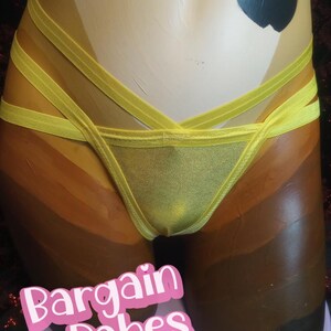 Puede incluir: Conjunto de lencería amarilla con diseño de tiras. El conjunto presenta una braguita de corte triangular y un top a juego. El texto "Bargain Babes" es visible en la imagen.