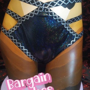May include: A mannequin torso displaying a black and iridescent swimsuit. The swimsuit features a geometric design with silver trim and a decorative bow. The words "Bargain Babes" are displayed in pink text at the base.