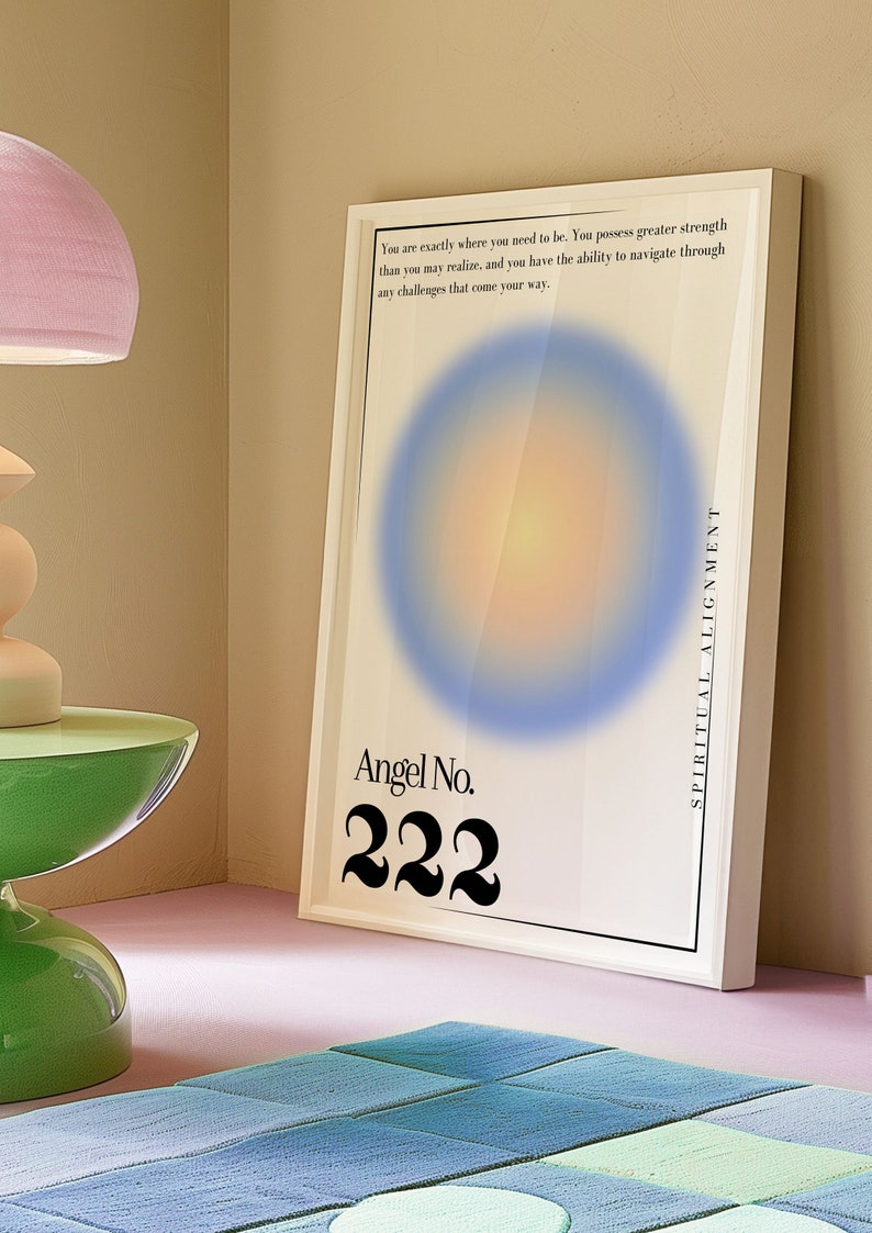 May include: A white framed poster with a blue and yellow gradient circle in the center. The text "Angel No. 222" is printed in black below the circle. The text "You are exactly where you need to be. You possess greater strength than you may realize, and you have the ability to navigate through any challenges that come your way." is printed in black at the top of the poster. The text "SPIRITUAL ALIGNMENT" is printed vertically on the right side of the poster.