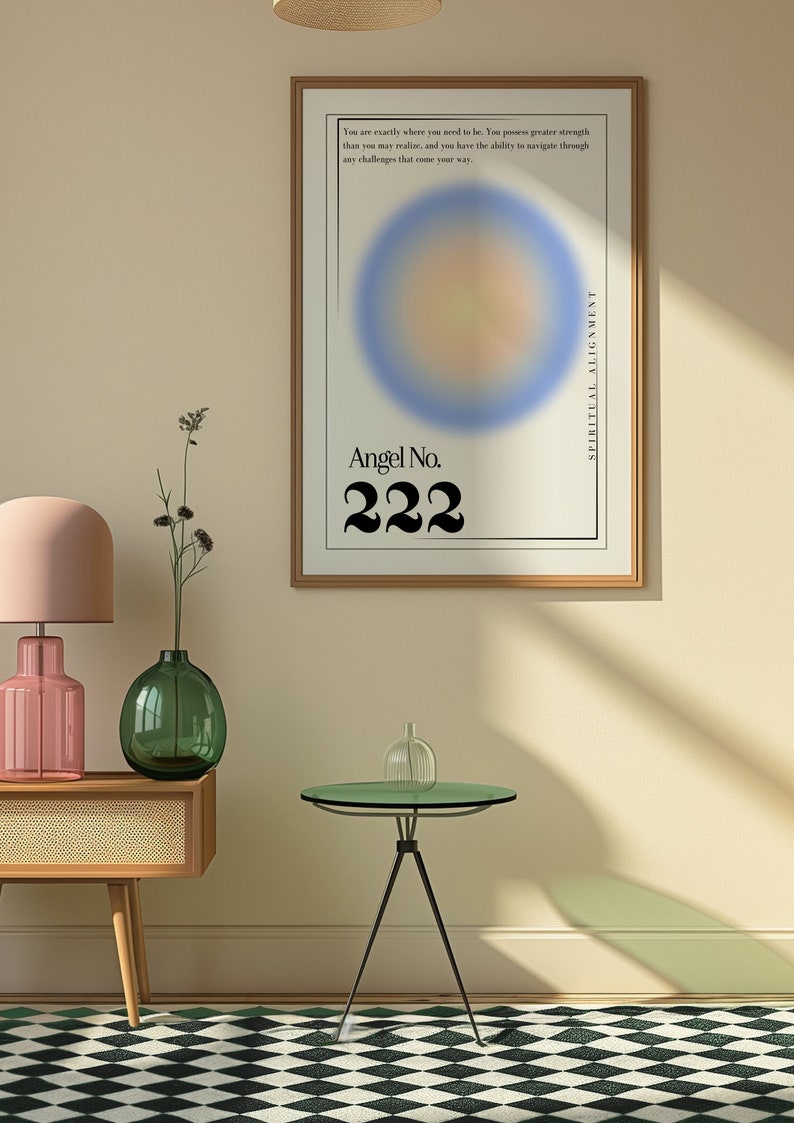 May include: A framed poster with a blurred blue, yellow, and orange circle in the center. The poster has the text "Angel No. 222" and "Spiritual Alignment" on it. The poster is hanging on a light beige wall with a wooden floor and a black and white checkered rug.