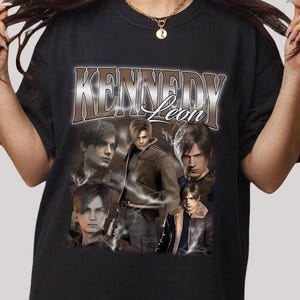 May include: Black t-shirt featuring a graphic design with the text "Kennedy Leon" in a brown and white font. The design includes multiple images of a person in various poses, with lightning bolt accents.