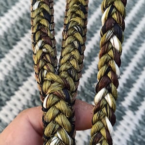 Puede incluir: Primer plano de una cuerda trenzada con un patrón de camuflaje en tonos de verde, marrón, negro y blanco.