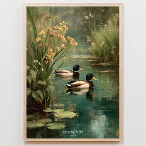 Op de afbeelding: Een ingelijste kunstdruk van een serene vijver met twee eenden. De eenden hebben groene koppen, bruine lichamen en gele snavels. Het water weerspiegelt het omringende groen en de gele bloemen. De tekst "arts by fritz" is onderaan zichtbaar.