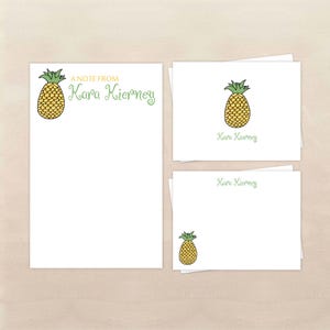 May include: White stationery set featuring a yellow pineapple illustration with green accents. The set includes a large notepad, a small notepad, and notecards. The name "Kara Kierney" is written in green script.