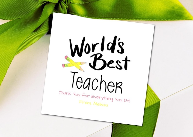 Puede incluir: Una tarjeta blanca con texto negro que dice "World's Best Teacher" con dos l&aacute;pices amarillos cruzados. El texto "Thank You for Everything You Do!" est&aacute; escrito en rosa debajo del texto principal. El texto "From Melissa" est&aacute; escrito en amarillo debajo del texto rosa.