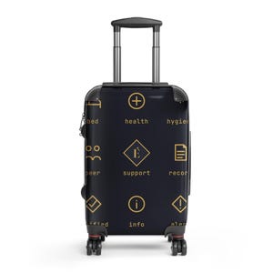 May include: A dark navy blue rolling suitcase with a retractable handle and four wheels. The exterior features a repeating pattern of gold icons and text including health, support, info, and alert, with a central diamond logo containing the letter É.