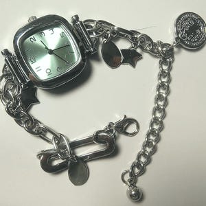 Reloj de pulsera con dijes de plata: elegante reloj de pulsera con cadena y esfera, accesorio diario elegante y funcional.