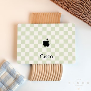 May include: A green and white chequered laptop skin with a black Apple logo and the word "Cisco" in black text.