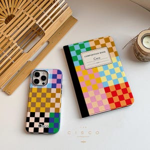 Puede incluir: Una funda de teléfono a cuadros de colores con la palabra "Cisco" impresa en ella. La funda está junto a una libreta con una cubierta a cuadros que dice "Composition Book Cisco".