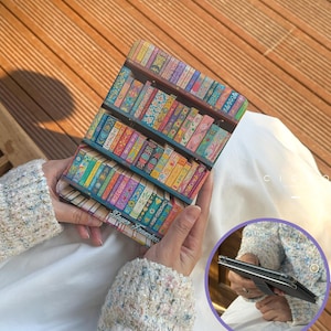 May include: A colorful phone case featuring a bookshelf design with rows of books in various colors and patterns. The case is held in a person's hands, with the text "Sloyer Francisco" visible on the bottom.