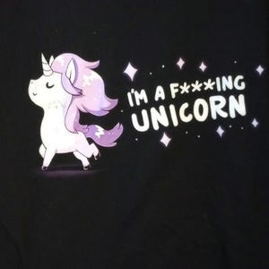 May include: Black graphic tee featuring a cartoon unicorn with a white body, a horn, and purple mane and tail. The text "I'M A F***ING UNICORN" is printed in white, with diamond shapes scattered around the text.