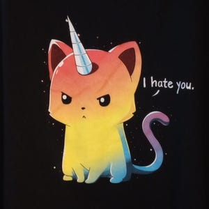 May include: A cartoon illustration of a cat-unicorn hybrid with a rainbow gradient design. The cat has an angry expression and a silver horn. The text "I hate you." is in a speech bubble. The background is black.