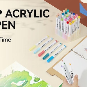 Pode incluir: Um conjunto de 90 marcadores acr&iacute;licos de ponta de pincel em uma variedade de cores. Os marcadores est&atilde;o em um recipiente de pl&aacute;stico transparente e s&atilde;o etiquetados como "Acrylic Marker Set".