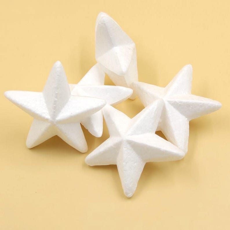 May include: Four white foam star shapes, each with five points. The stars are arranged in a pile, with one star on top of the others.
