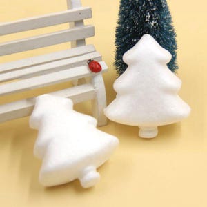 May include: Two white foam Christmas tree shapes. The trees are approximately 7.5 cm tall and are ideal for crafting.