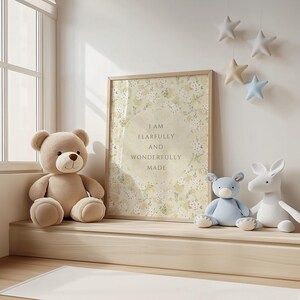 May include: A framed print with a floral background and the text "I am fearfully and wonderfully made". The print is hanging on a white wall with a stuffed bear, a blue stuffed animal, and a white stuffed animal sitting on a wooden shelf below it.