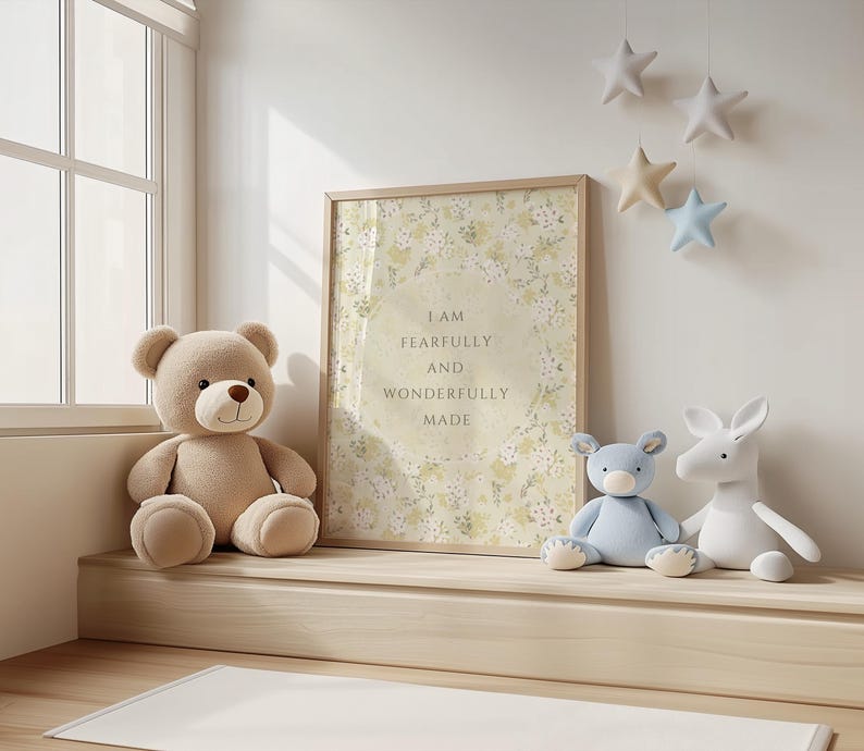 May include: A framed print with a floral background and the text "I am fearfully and wonderfully made". The print is hanging on a white wall with a stuffed bear, a blue stuffed animal, and a white stuffed animal sitting on a wooden shelf below it.