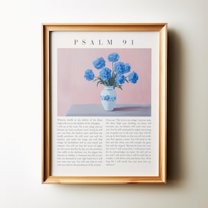 Pode incluir: Uma impressão emoldurada do Salmo 91, uma passagem da Bíblia, com um vaso de flores azuis sobre um fundo rosa. O texto diz: "Aquele que habita no abrigo do Altíssimo, descansará à sombra do Todo-Poderoso. Direi ao Senhor: O meu refúgio e a minha fortaleza, o meu Deus, em quem confio.  Ele certamente te livrará do laço do caçador e da peste mortal.  Ele te cobrirá com as suas penas, e debaixo das suas asas encontrarás refúgio.  A sua fidelidade será o teu escudo e o teu escudo.  Não temerás o terror da noite, nem a flecha que voa de dia, nem a peste que anda na escuridão, nem a mortandade que assola ao meio-dia.  Mil cairão ao teu lado, e dez mil à tua direita; mas a ti não chegará.  Com os teus olhos olharás, e verás a recompensa dos ímpios."