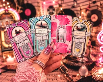 May include: Four rectangular cards featuring illustrations of vintage jukeboxes in pink, blue, and yellow. The cards display text including Here Now & Forever, All I Need, I Want to be Close to You, Intimacy, and I'm Impulsive, with musical note patterns.