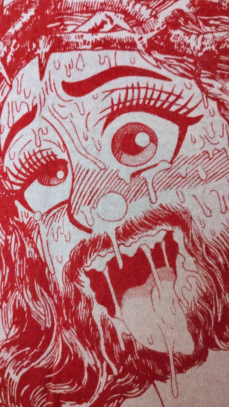 Pu&ograve; includere: Primo piano di una stampa grafica rossa e bianca di un viso con una grande bocca aperta e vernice rossa che cola. Il viso ha occhi grandi con pupille rosse e ciglia lunghe.