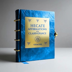 May include: A blue grimoire with gold accents and the text "HECATE AFFIRMATIONS FOR CLAIRVOYANCE". The book has a gold clasp and gold rings along the spine. A blue ribbon bookmark is visible.