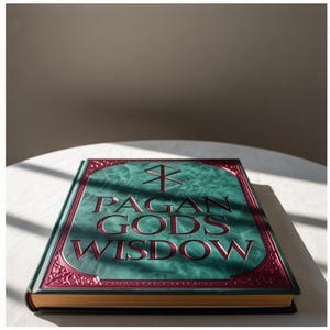 May include: A hardcover book titled "Pagan Gods Wisdom" rests on a white surface. The book has a teal cover with a decorative border and embossed text in a deep red hue. The book's spine is gold.