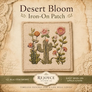 May include: A square iron-on patch featuring embroidered desert flora, including a central cactus and various pink and orange flowers on a beige fabric background. The text Desert Bloom Iron-On Patch is visible above, with Rejoyce Studio AZ branding below.
