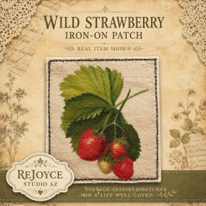 May include: A square iron-on patch featuring a printed illustration of a wild strawberry plant with green leaves and three red strawberries. The patch has a visible black stitched border and is set against a light beige fabric background.