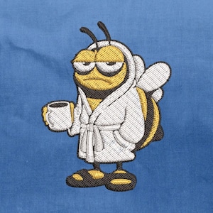 May include: Embroidered patch featuring a cartoon bee wearing a white robe and holding a coffee cup. The bee has a grumpy expression and is colored yellow, black, and white. The background is a solid blue.