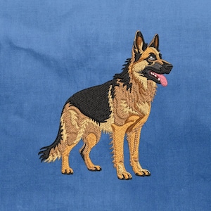 Może przedstawiać: Haftowany owczarek niemiecki na niebieskim tle. Pies przedstawiony jest w pozycji stojącej, z czarno-brązowym umaszczeniem i różowym językiem. Haft szczegółowo przedstawia sierść, oczy i rysy twarzy psa.