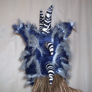 May include: A blue and white faux fur hat with black and white zebra-print horns. The hat is made of soft, fluffy material and has a unique, whimsical design.