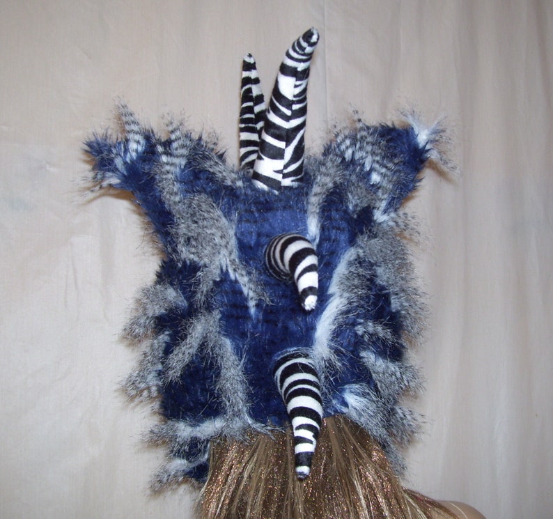 May include: A blue and white faux fur hat with black and white zebra-print horns. The hat is made of soft, fluffy material and has a unique, whimsical design.