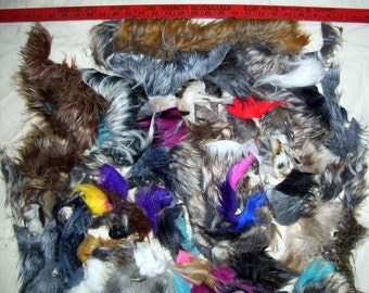 May include: A collection of various fur and feather trims in a variety of colors, including brown, gray, white, blue, purple, and pink. The trims are arranged in a pile on a white surface.
