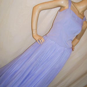 May include: A lavender-colored sleeveless gown with a fitted bodice and a flowing skirt. The skirt is pleated and has a subtle sheen.