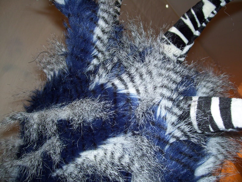 May include: A blue and white striped furry hat with a long, black and white striped tail.