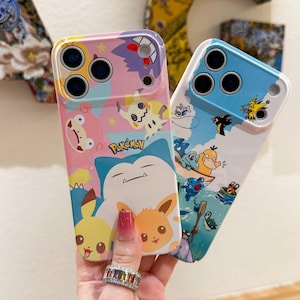 May include: Two colorful phone cases featuring Pok&eacute;mon characters. One case has a pink and purple background with Pikachu, Mimikyu, and Snorlax. The other case has a blue and white background with various water-type Pok&eacute;mon. The cases have a glossy finish.