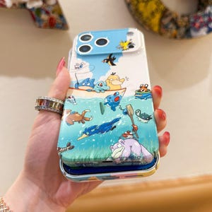 May include: A colorful phone case featuring a cartoon aquatic scene with various creatures in a boat and swimming in the water. The case has a blue sky background and a white border.