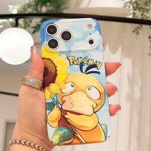 May include: A phone case featuring a cartoon Psyduck character holding a sunflower, set against a blue sky background. The case has the word "Pok&eacute;mon" printed on it. The case is designed to fit a smartphone.