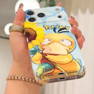 May include: A phone case featuring a cartoon Psyduck character holding a sunflower, set against a blue sky background. The case has the Pokemon logo and a yellow, orange, and blue color scheme.