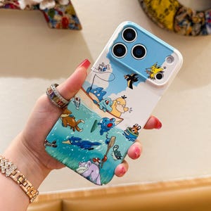 May include: A white and blue phone case featuring a cartoon illustration of various characters in a boat on the water. The case has a blue top section with three camera cutouts and a white border.