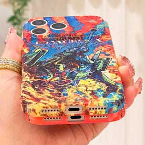 May include: A colorful phone case with a vibrant design featuring a detailed illustration. The case has a red border and a complex graphic with blue, green, and yellow hues. The text "EVANGELION" is visible on the case.