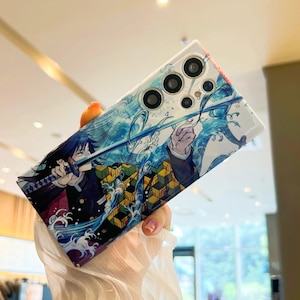 Pu&ograve; includere: Una custodia per telefono con un design anime blu e bianco che presenta un personaggio con una spada. La custodia ha un design della fotocamera multi-obiettivo.