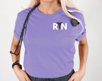 May include: A purple t-shirt with a white "RN" graphic and a black medical symbol. The shirt is worn by a person with a stethoscope around their neck.