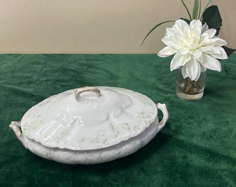 Antica leccavite ovale in porcellana Warwick, con coperchio. Prodotta a Wheeling, Virginia Occidentale. Decori a spirale in rilievo bianco sporco, fiori verdi e manici in oro spazzolato. Anni &#39;10.