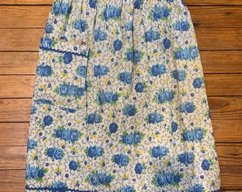 Vintage blauwe bloemenschort met voorzak en roklengte van 60 cm. Dit handgemaakte schort heeft plooien en rickrack aan de zak en zoom. jaren vijftig