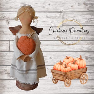 Puede incluir: Una muñeca de tela con cabello de lana rubia y alas oscuras, vistiendo un vestido blanco con rayas grises, sosteniendo una calabaza naranja. Al lado, un carro de madera lleno de calabazas. Texto: Chickadee Primitives MY HOME TO YOURS.