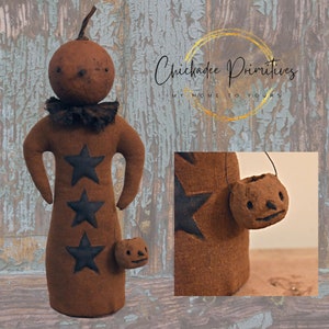Op de afbeelding: Een bruine stoffen pompoendoll met zwarte sterren en een klein pompoen-emmertje. De pop staat op een houten achtergrond met de tekst "Chickadee Primitives My Home To Yours".