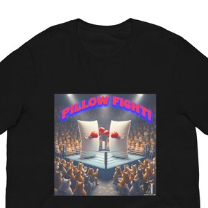 May include: Black t-shirt featuring a colorful graphic of a pillow fight scene. Two pillows are in a boxing ring, wearing boxing gloves, with the text "PILLOW FIGHT!" above them. The crowd is made up of cat-like figures.
